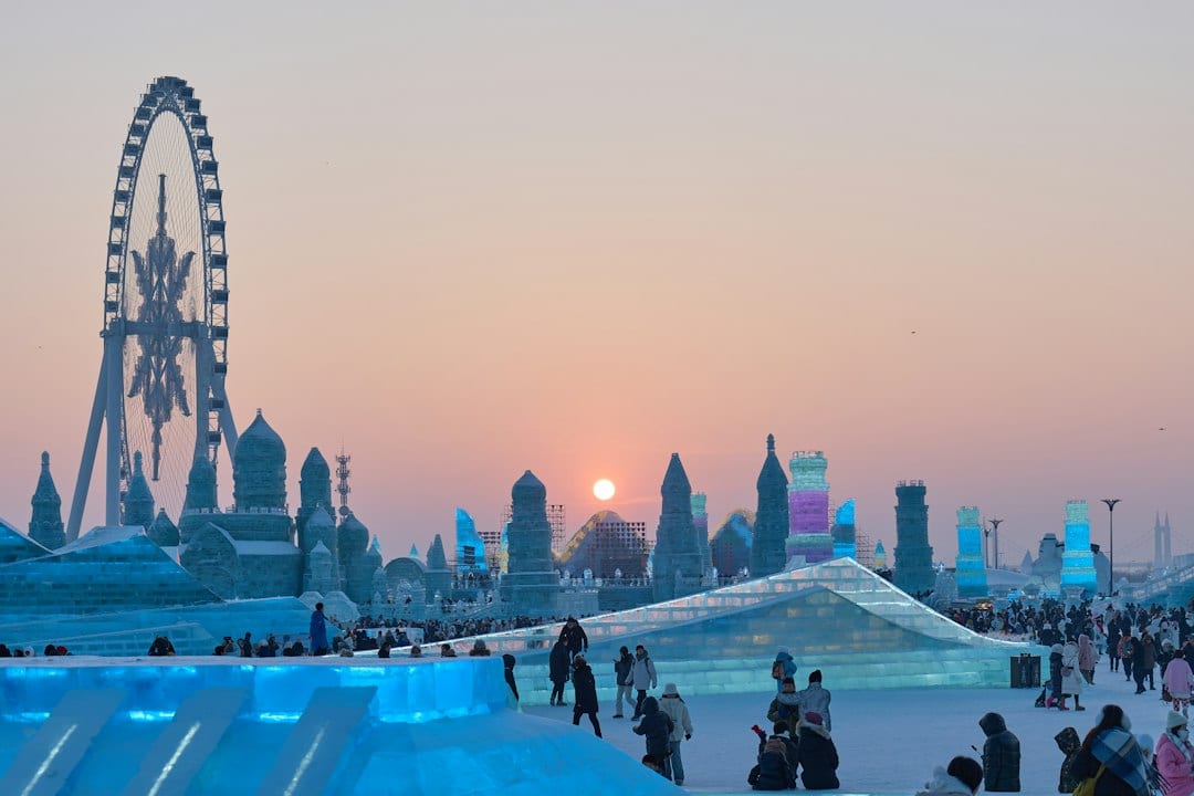 Illuminated ice sculptures at Harbin Ice Festival at night with families walking among frozen palaces