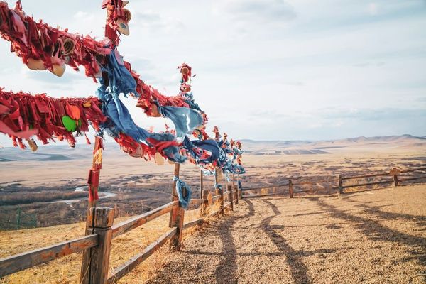 A wooden fence with red and blue streamers on the Inner Mongolia grassland