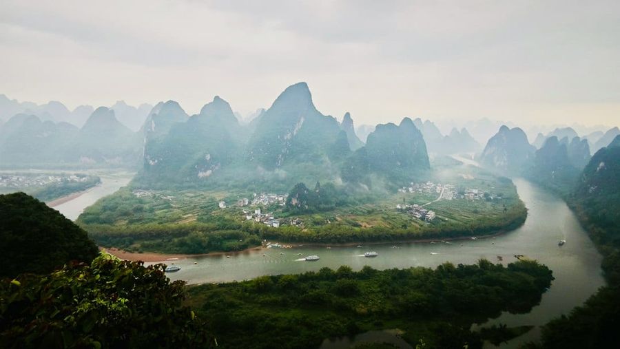 Misty karst mountains and a winding river surround a village